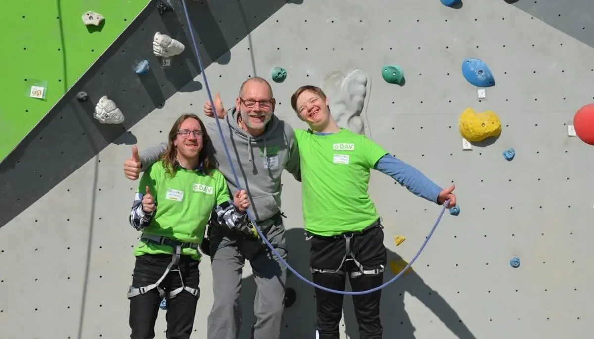 Zwei Kletterer und ein Trainer stehen vor einer Kletterwand und strahlen in die Kamera | © Ralf Holtgrefe