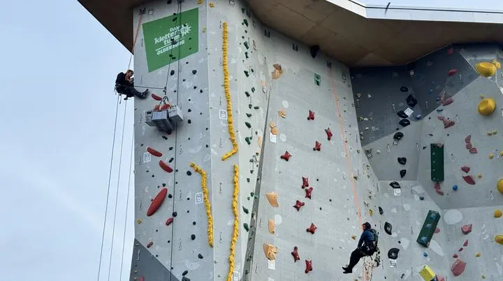 Zwei Kletterer schrauben die Griffe vom Kletterturm ab | © Kletterzentrum