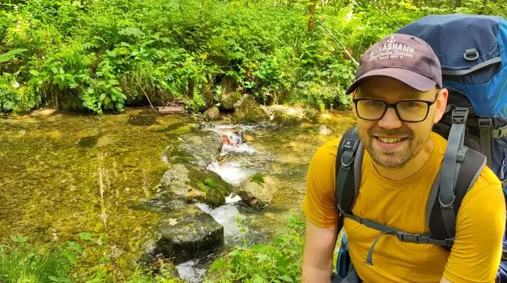 Patrik Schönfeld, im Hintergrund ein Bachlauf | © Patrik Schönfeld