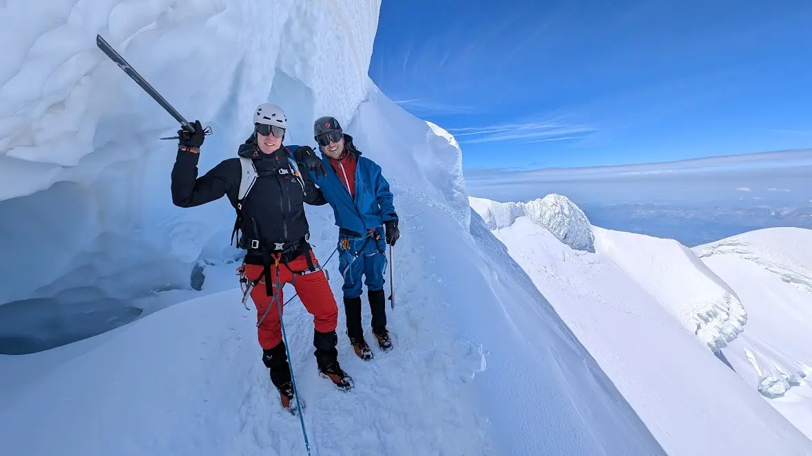 Zwei Bergsteiger stehen auf einem schneebedeckten Gipfelpfad  | © Tobias Nordhausen