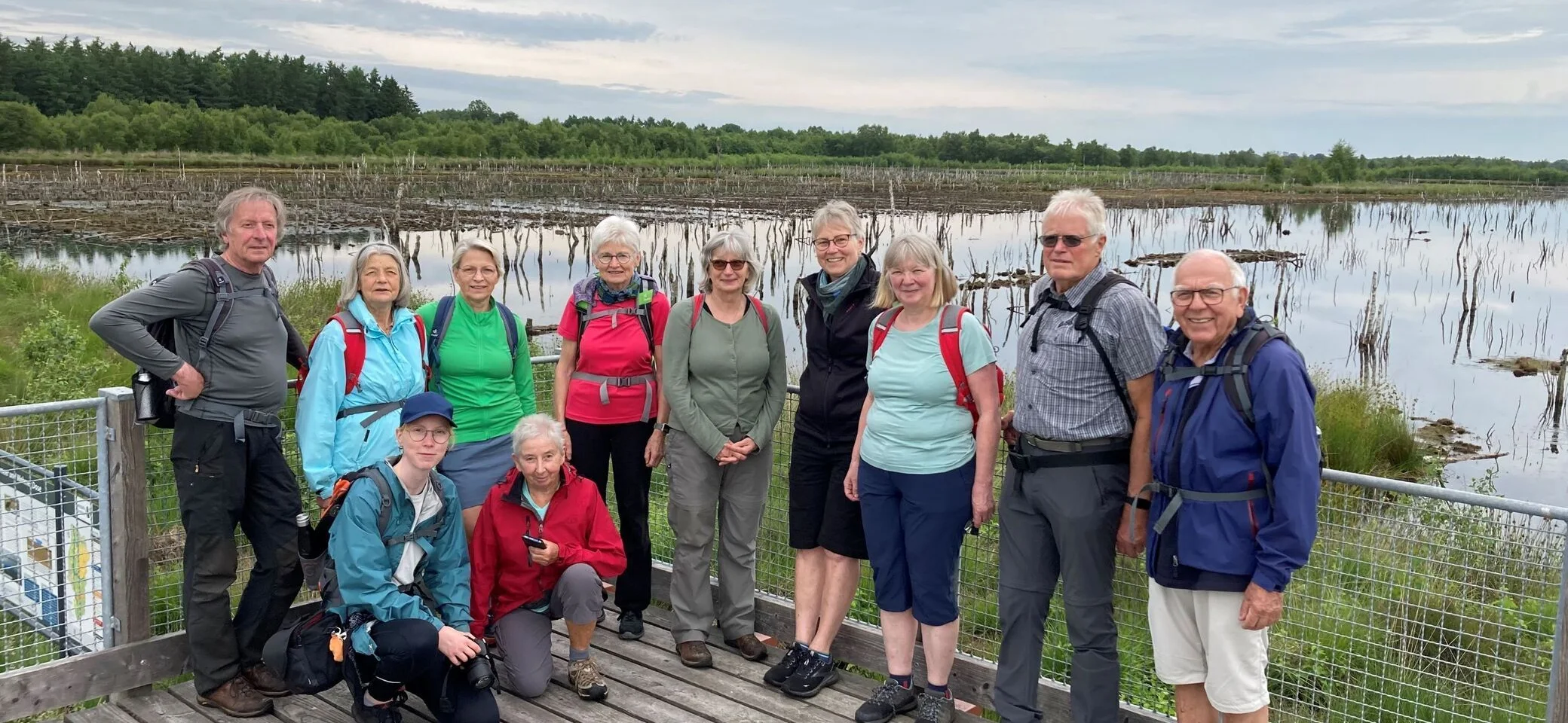 Eine Wandergruppe steht auf einem erhöhten Ausblick, im Hintergrund ist das Theikenmeer zu sehen | © Frank Göhrisch