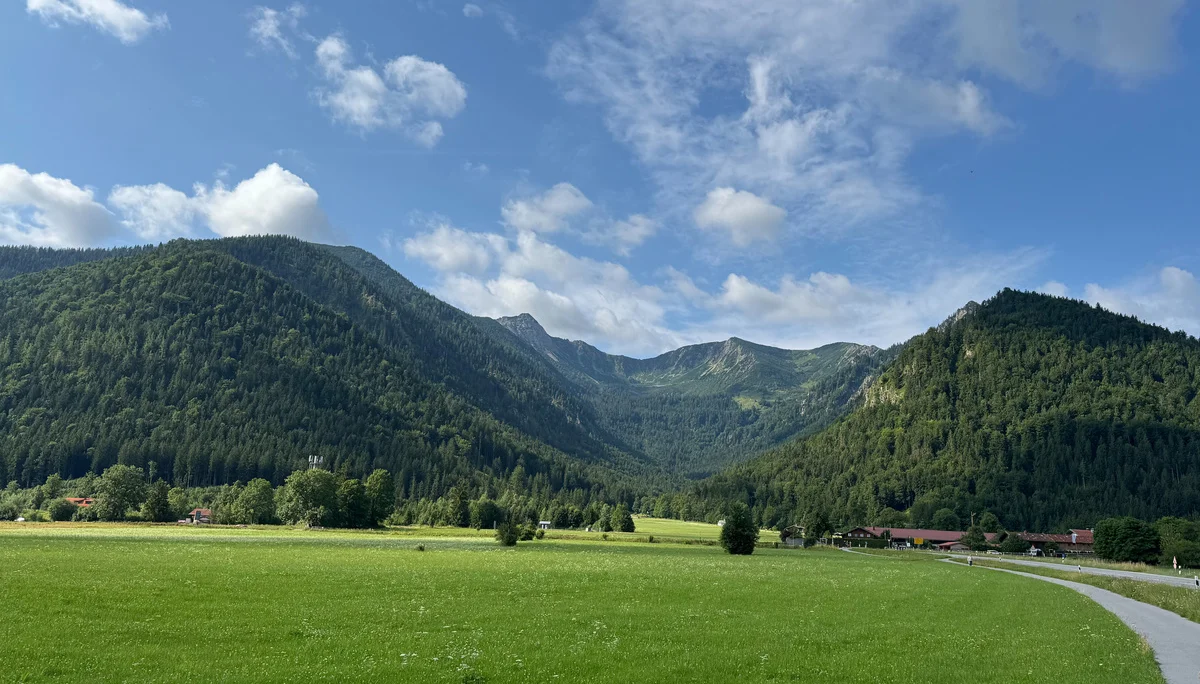 Wiese, daneben eine kleine Straße, im Hintergrund Berge | © Patrick Schönfeldt