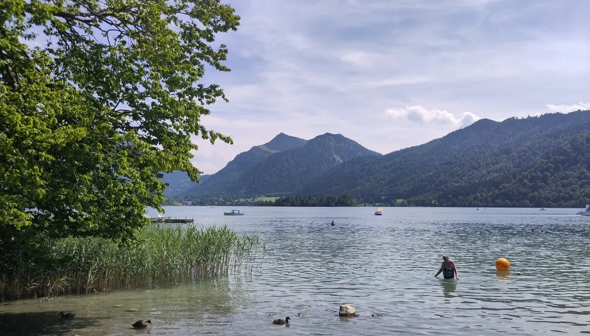 Ein See mit einem Badenden, im Hintergrund Berge | © Patrick Schönfeldt