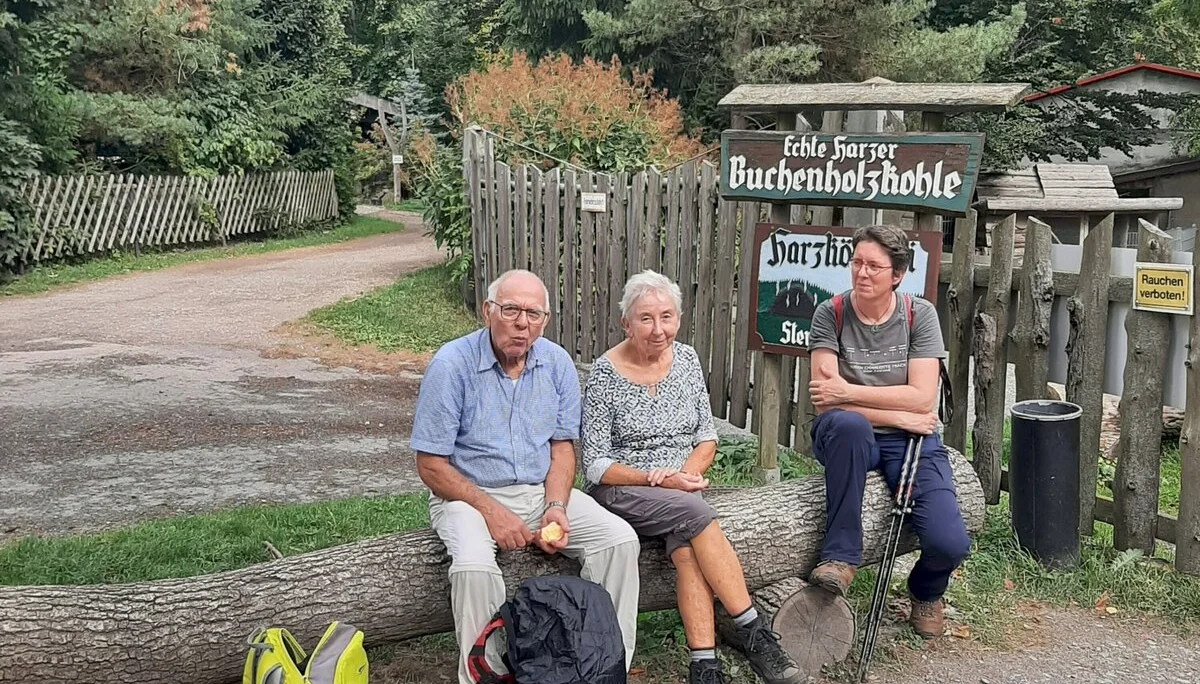 Teilnehmer einer Wanderung sitzen vor dem Eingang zum Köhlereimuseum im Harz | © Beate Straube