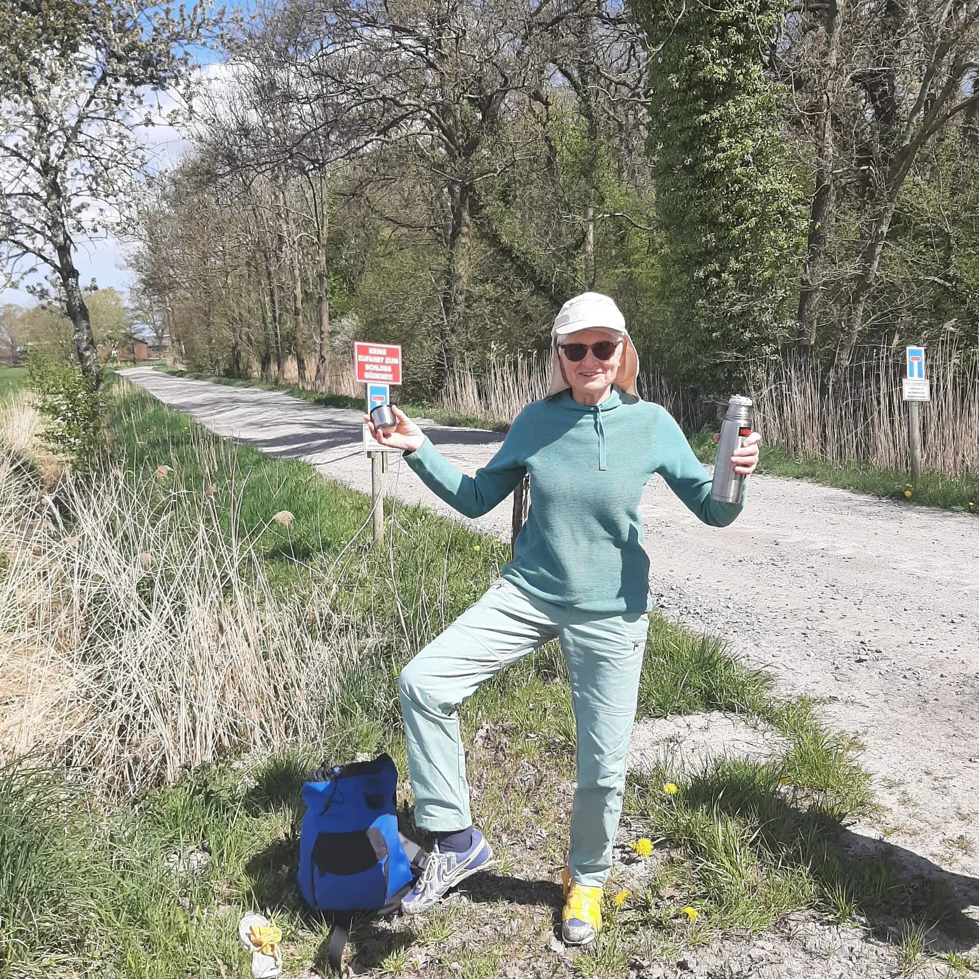 Eine Wanderin steht auf einem Weg, in der Hand hält sie eine Thermosflasche | © Beate Straube