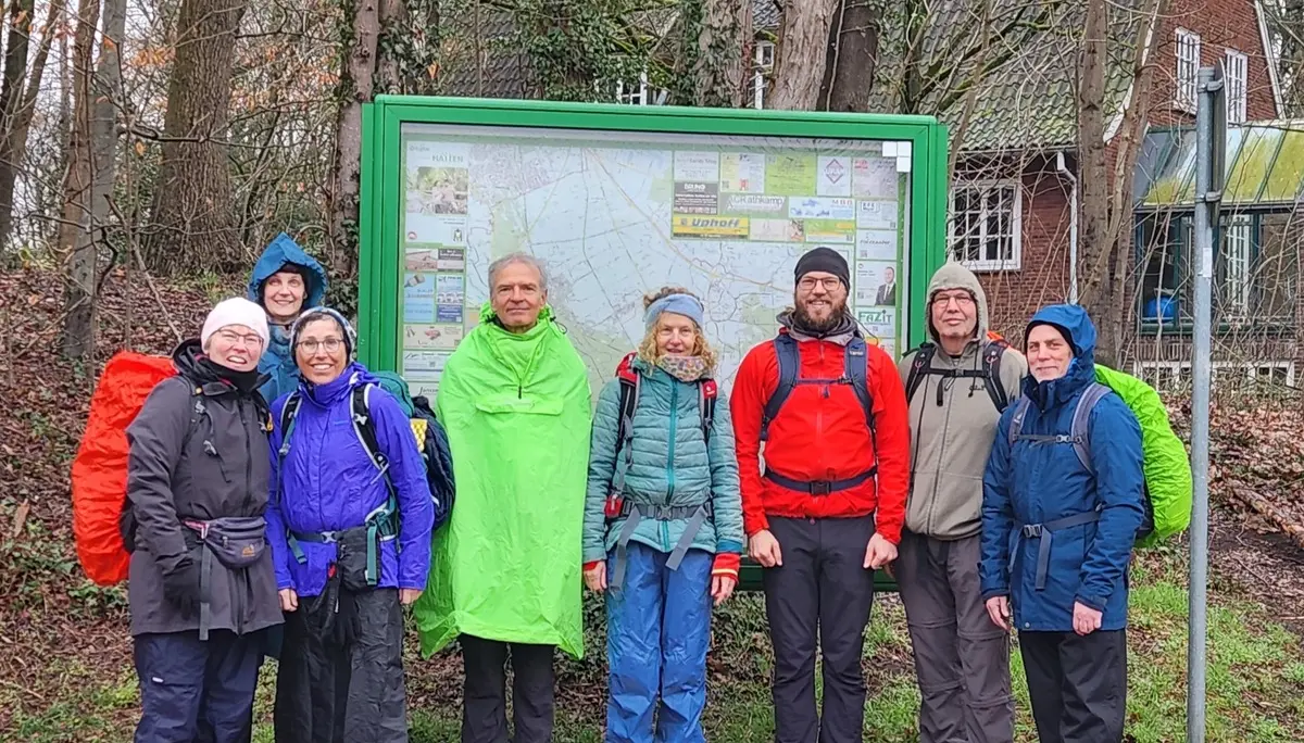 Wandergruppe vor einem Schaukasten mit Ortsbeschreibung am Bahnhof Sandkrug | © Edda Potthast